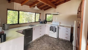 A kitchen with wooden beams, a large window, and a stone-patterned floor.