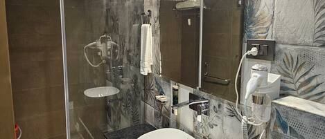 A modern bathroom with a glass-enclosed shower, a large round sink, and a mirror above the sink.