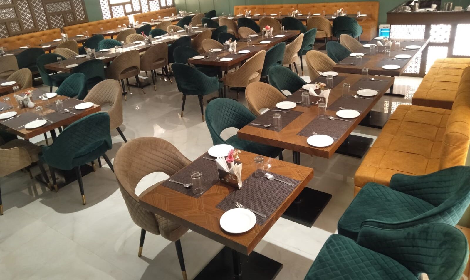 Un restaurante espacioso con varias mesas y sillas, una zona de bar y una sección de estar con sofás acolchados.
