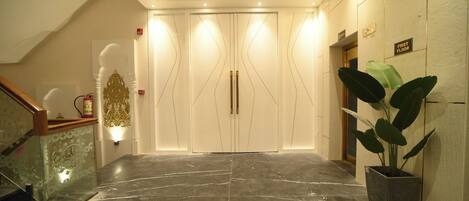 Un moderno vestíbulo de hotel con suelo de mármol, una escalera y una gran planta en maceta.
