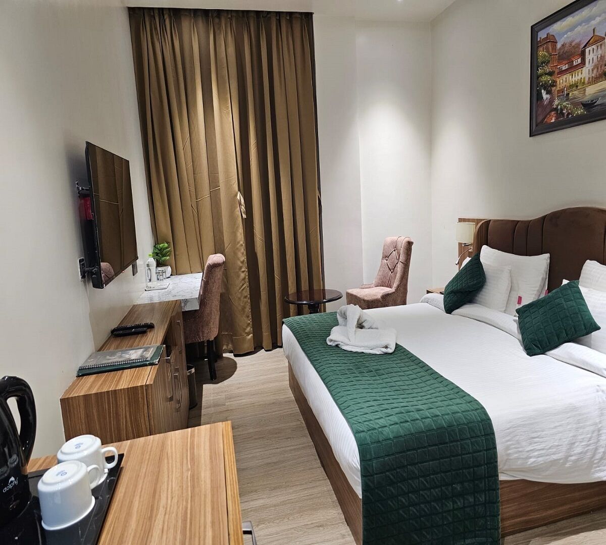 Une chambre d’hôtel avec un lit, un bureau, une chaise, une télévision et un tableau au mur.