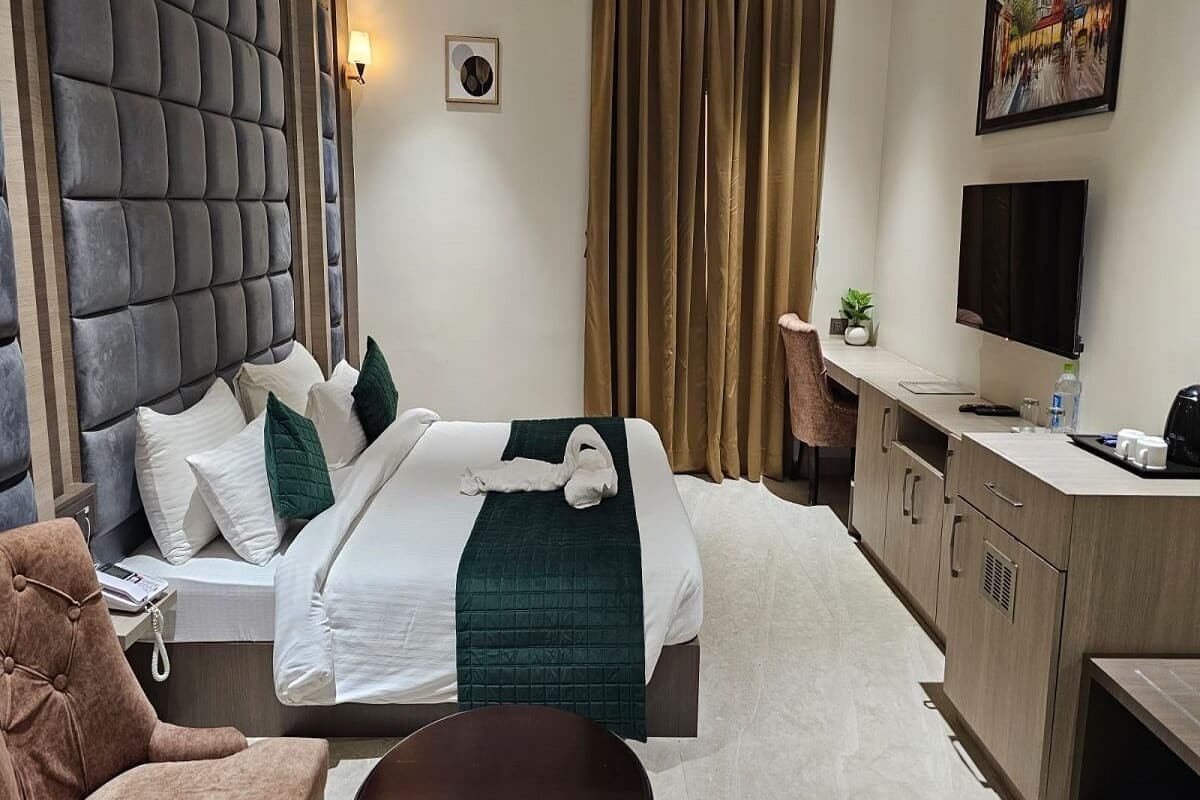 A hotel room with a large bed, a desk, a chair, a television, and a painting on the wall.
