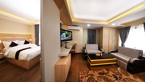 A modern hotel room with a bed, a sofa, a coffee table, a TV, and a desk. - Divine Kathmandu Hotel (Kathmandu)