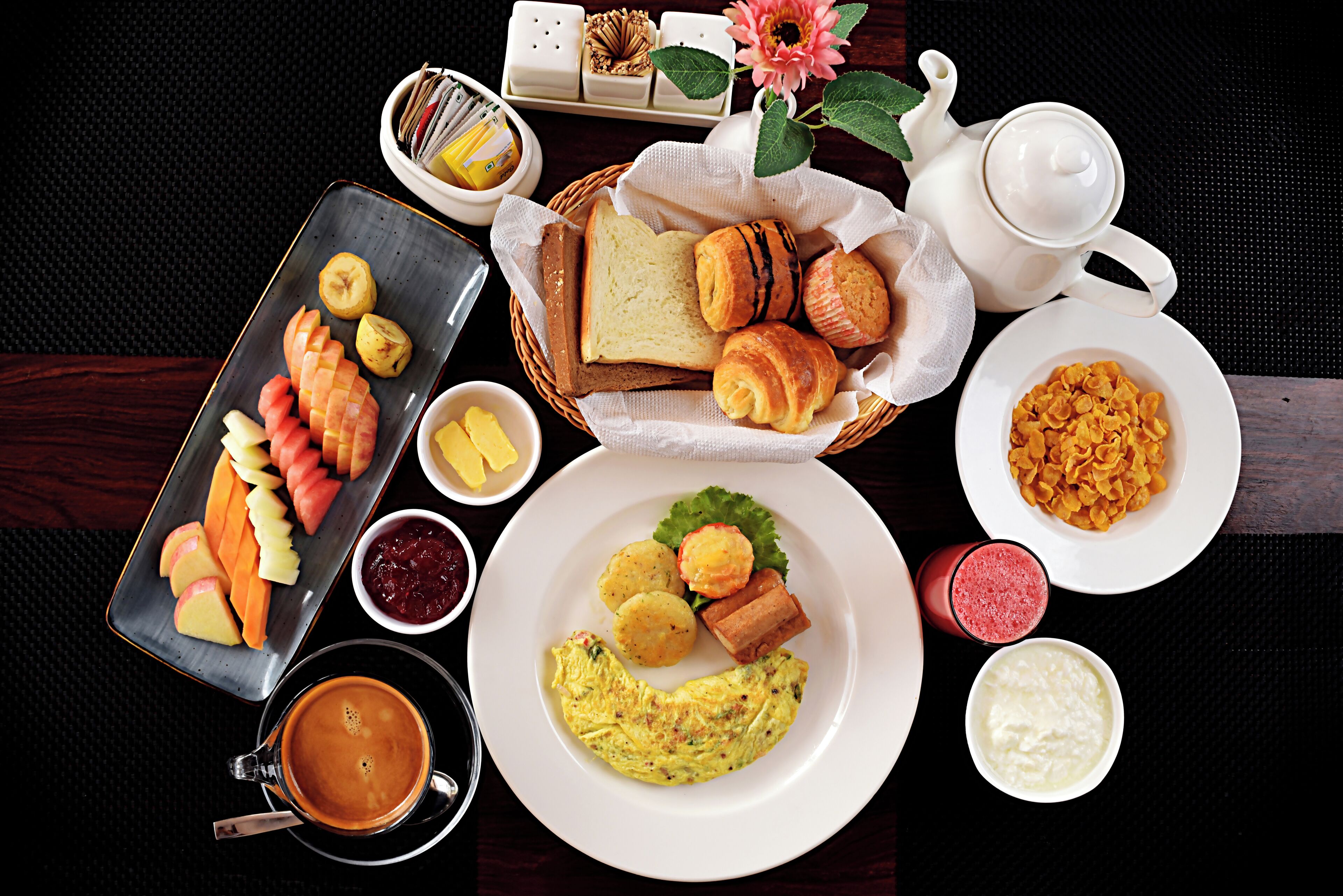 Desayuno con diferentes alimentos, una tetera y una taza de café.