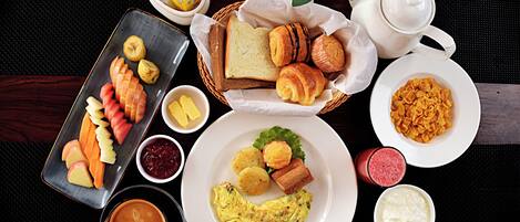 A breakfast setting with various food items, a teapot, and a cup of coffee.