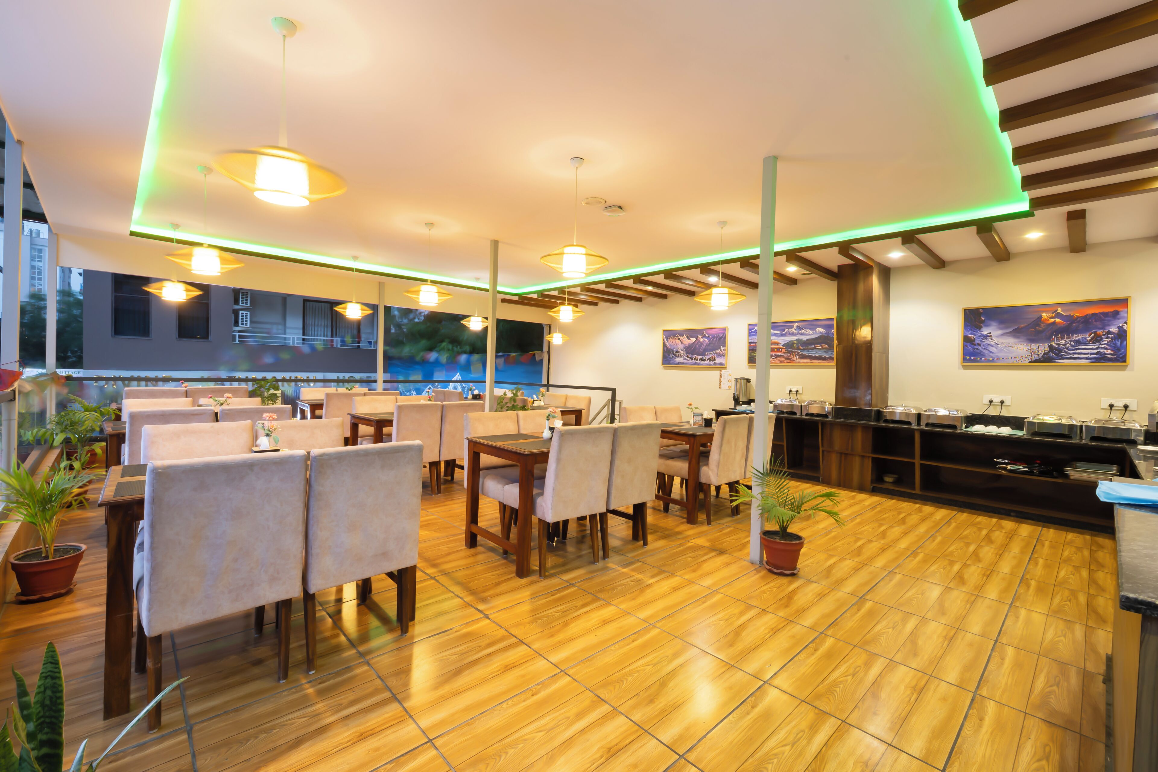 A restaurant with wooden flooring, beige chairs, and a buffet area.
