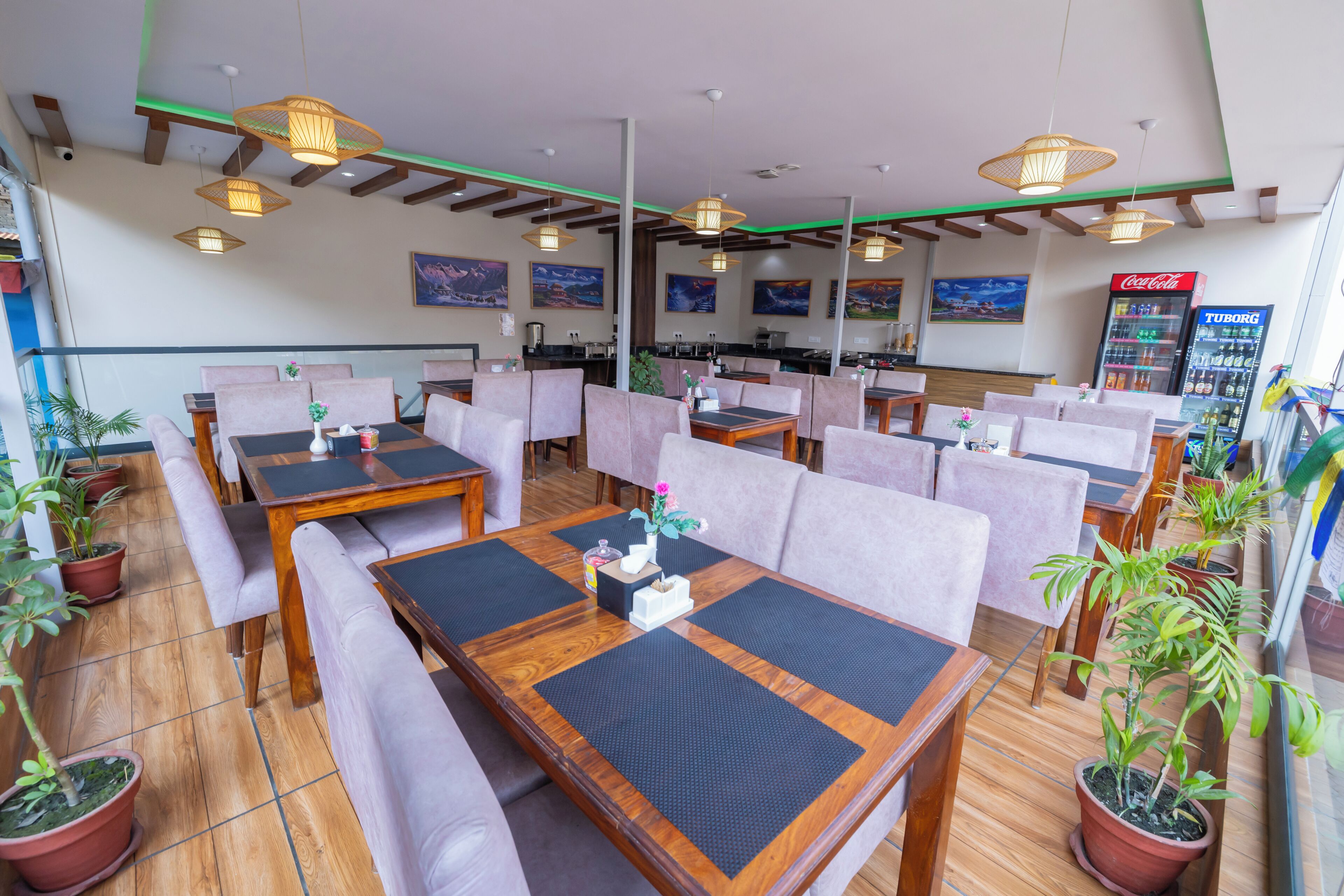 A restaurant with wooden tables, cushioned seating, and potted plants.