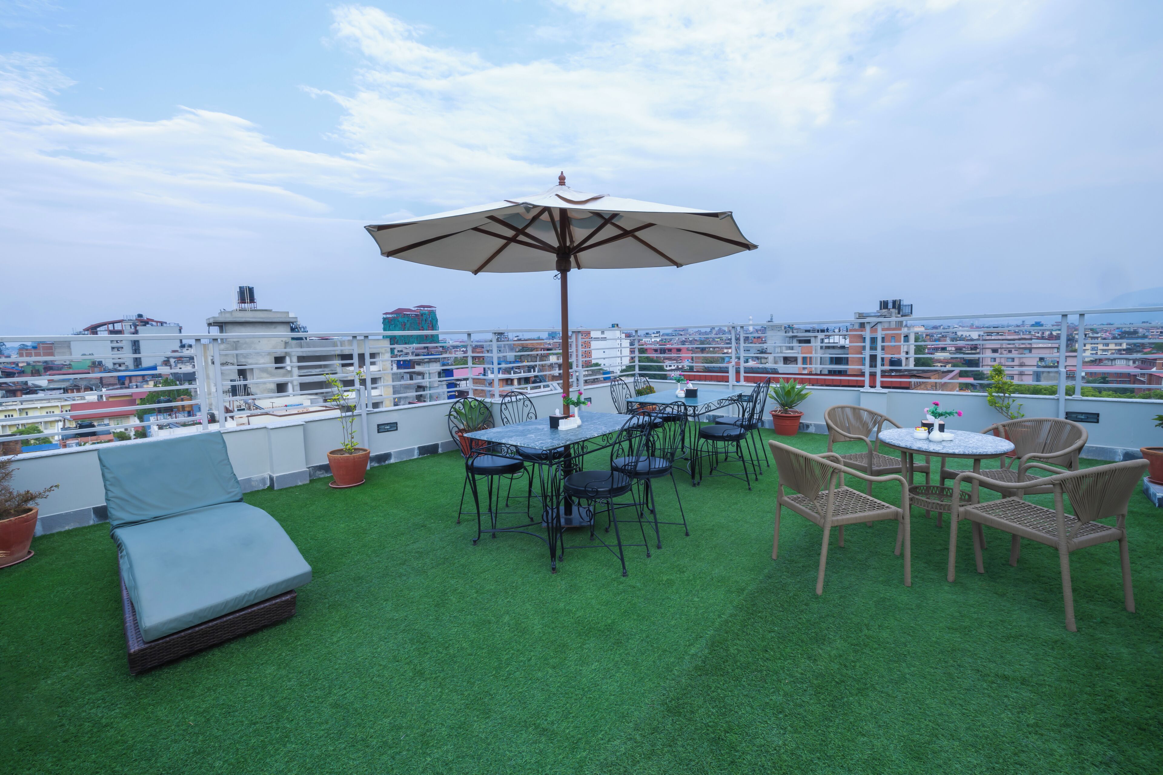 Una terrazza sul tetto con erba sintetica, un tavolo con sedie e un ombrellone.