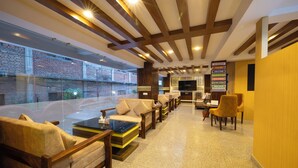 A modern lobby with a brick wall, wooden beams, and a seating area with sofas and armchairs. - Divine Kathmandu Hotel (Kathmandu)
