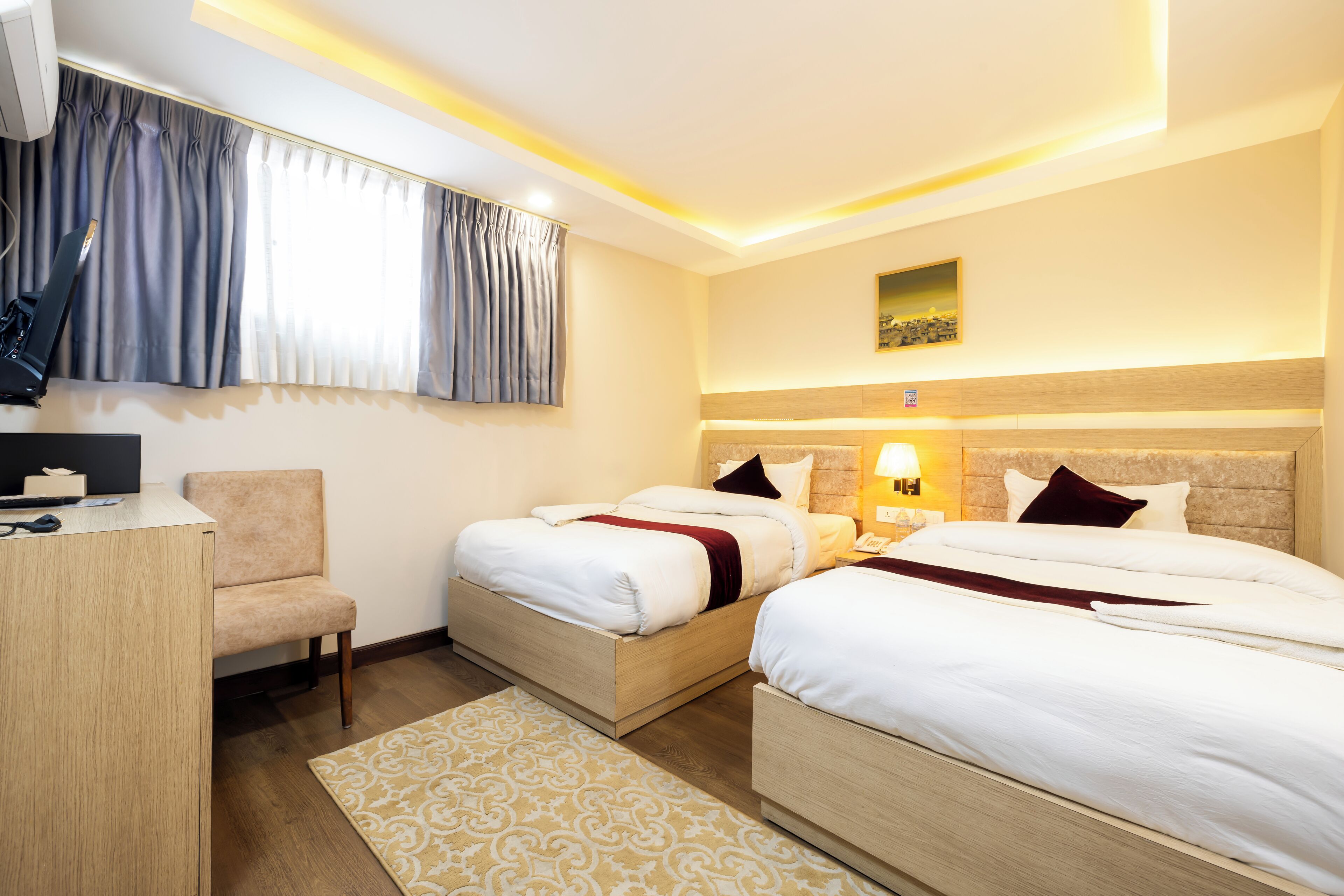 Une chambre d’hôtel avec deux lits, un bureau, une chaise et une fenêtre avec des rideaux.