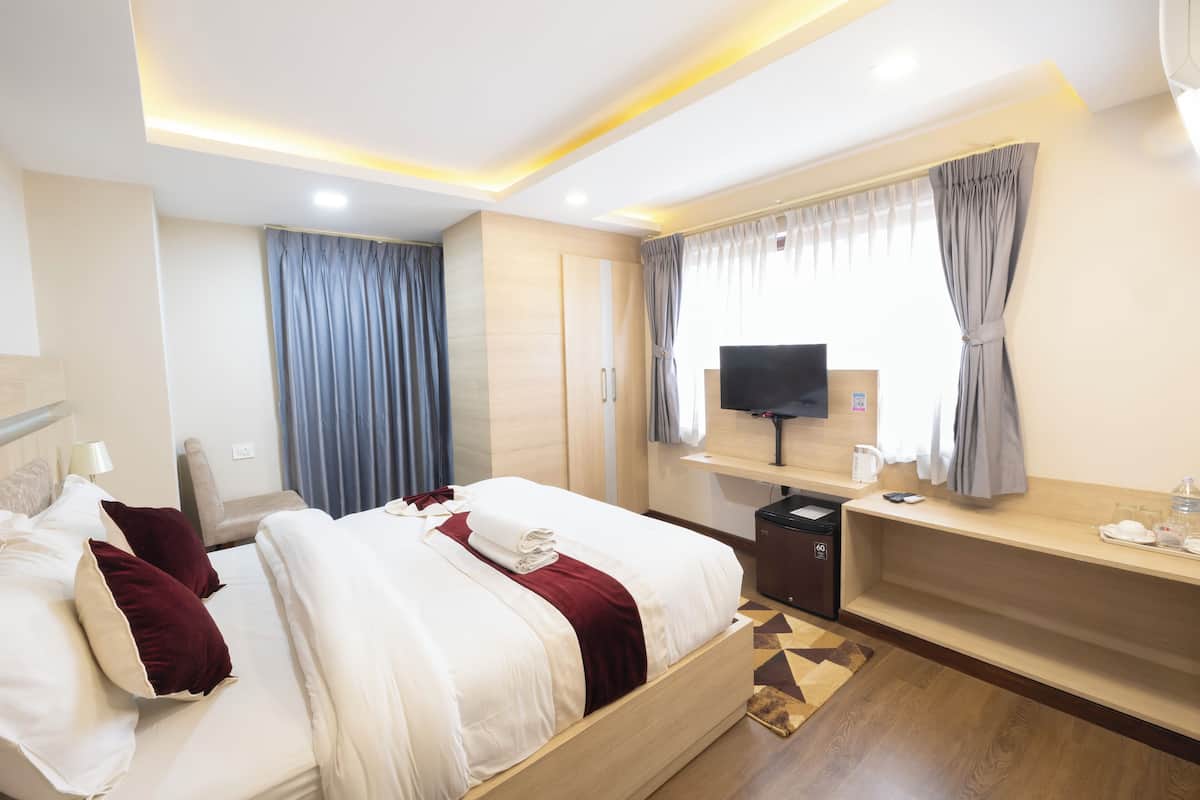 Quarto de hotel moderno com uma cama grande, escrivaninha, televisão e máquina de café.