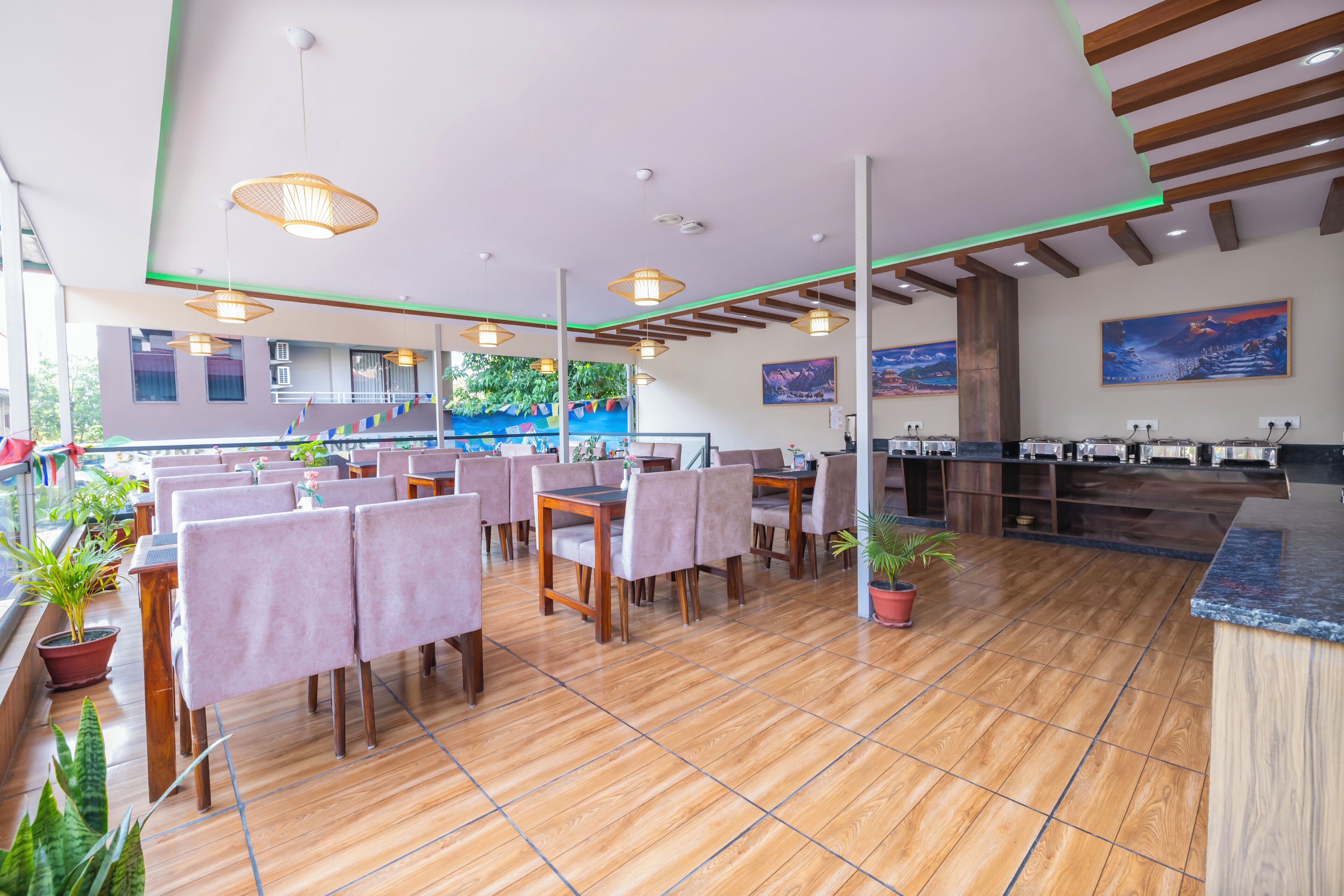 Een restaurant met houten vloeren, tafels met stoelen, hangende lampen en een toonbank met etenswaren.