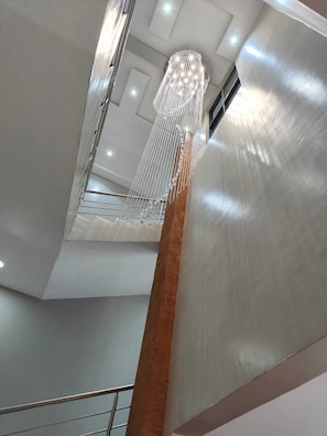 A modern interior with a high ceiling, a central column, and a hanging light fixture. - Hotel Lourdes Siaya (Siaya)