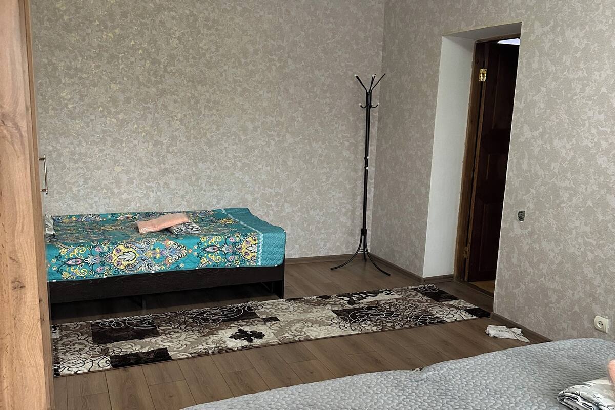 A bedroom with a bed, a coat rack, and a door.