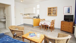 A compact living space with a kitchenette, dining area, and a television. - Die Ferienwohnung Nr. 02 im Haus Rugier in Göhren (Göhren)
