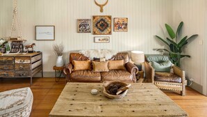Ein gemütliches Wohnzimmer mit braunem Ledersofa, einem Holztisch und einer rustikalen Einrichtung.