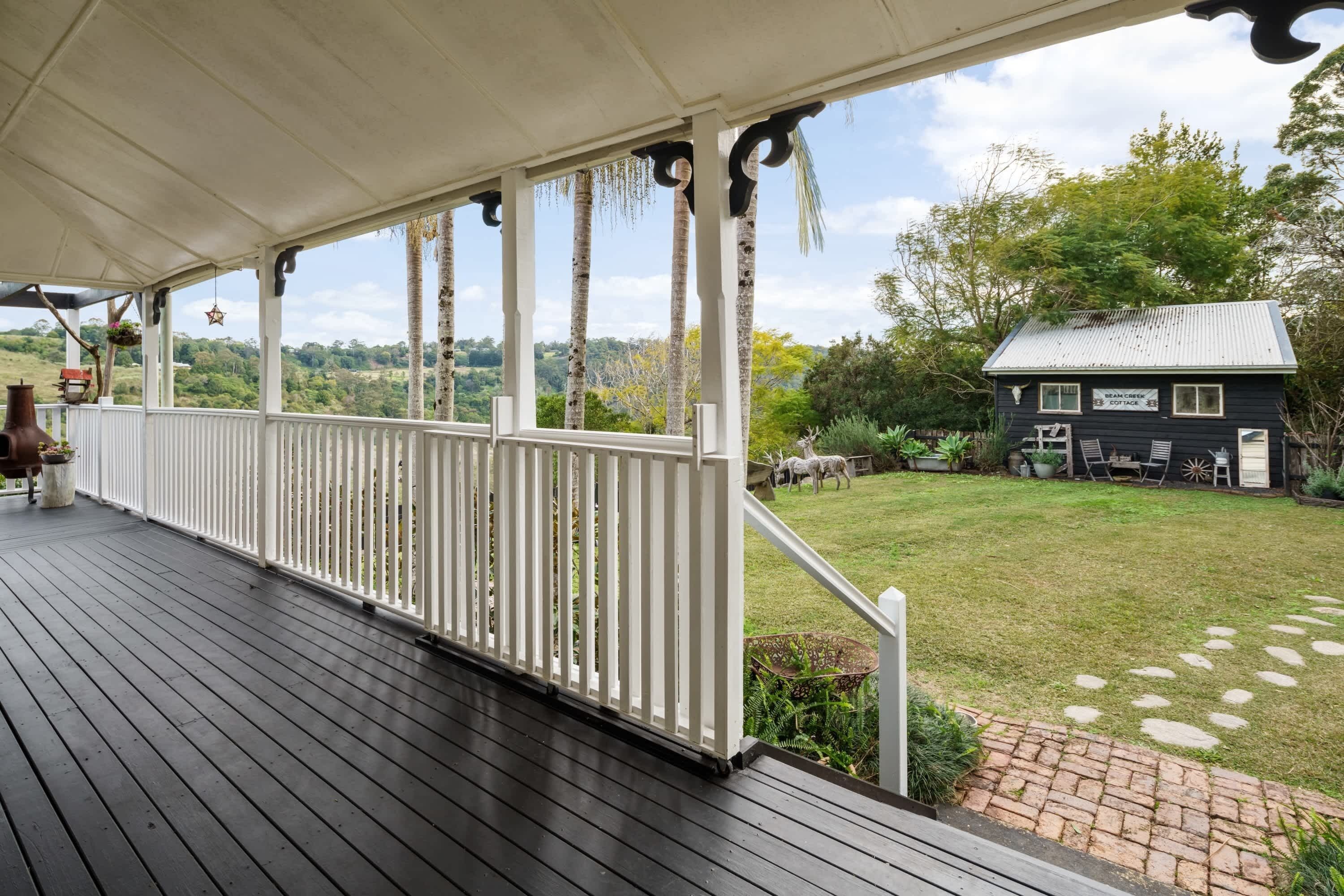 A covered porch with white railings and a view of a house with a sign that reads "B&B".