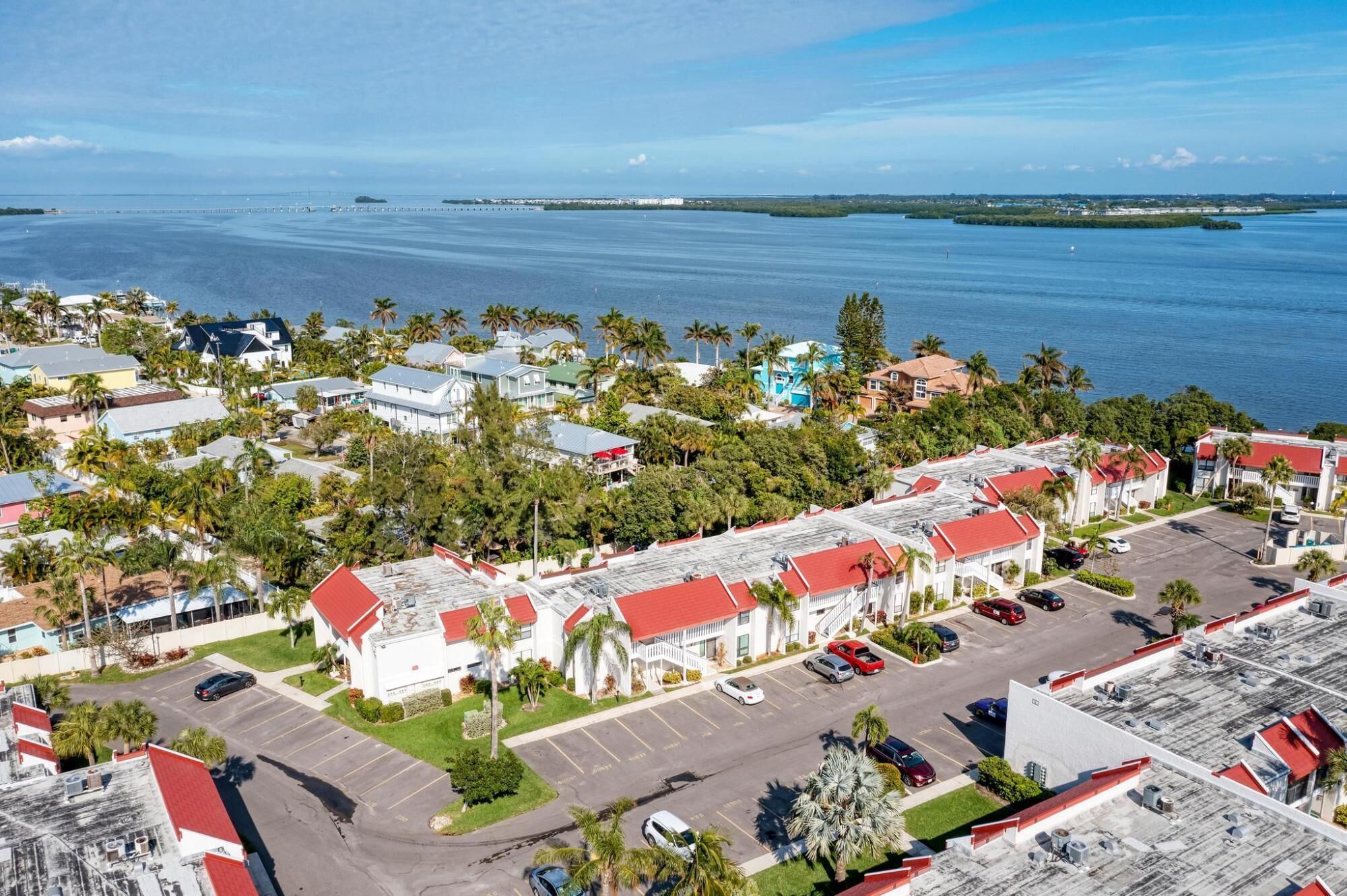 Vue aérienne d’un quartier résidentiel situé sur la côte, avec des maisons, un parking et une marina.