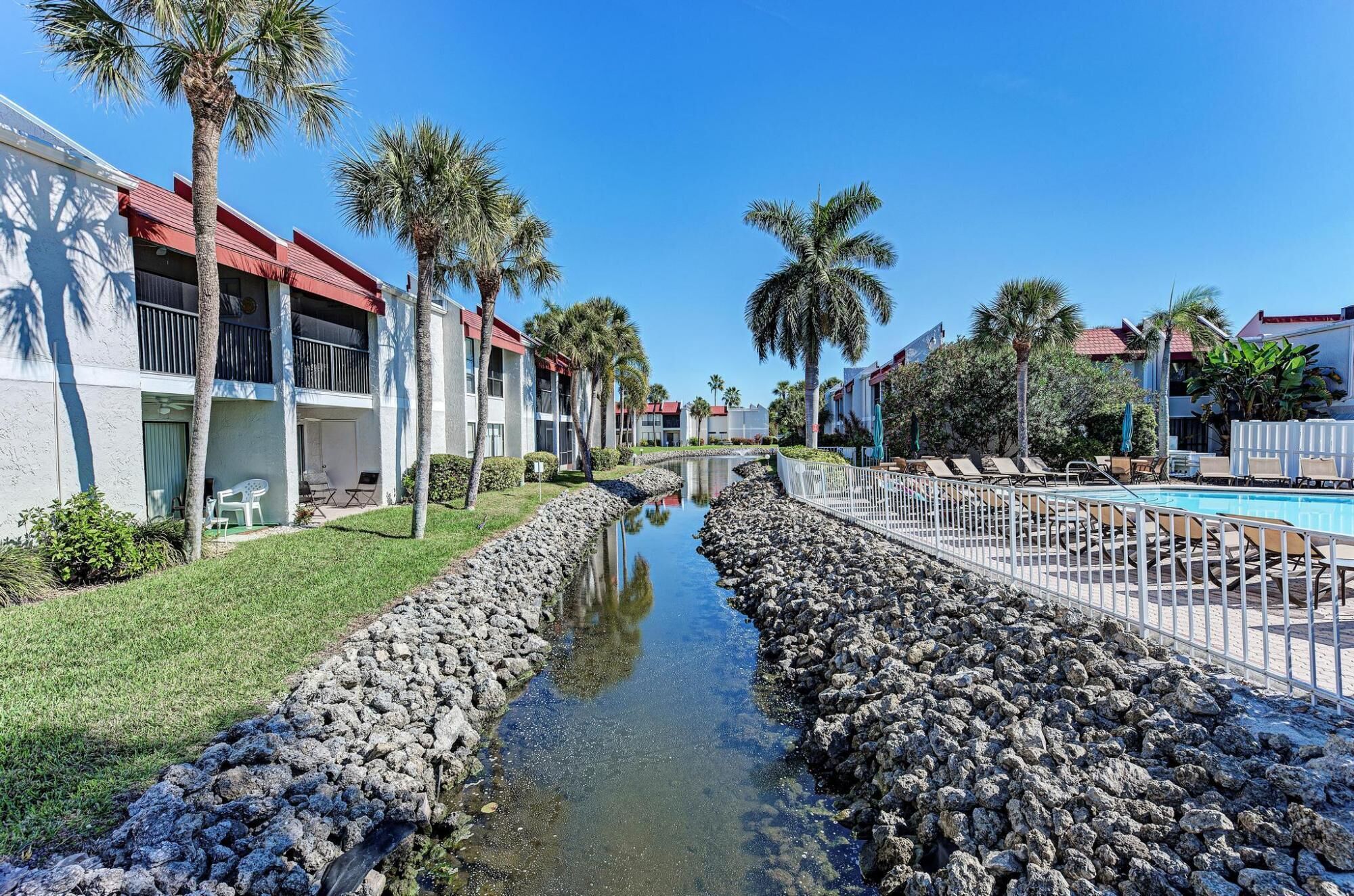 A hotel with a pool, palm trees, and a water channel.