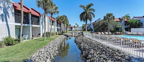 A hotel with a pool, palm trees, and a water channel.