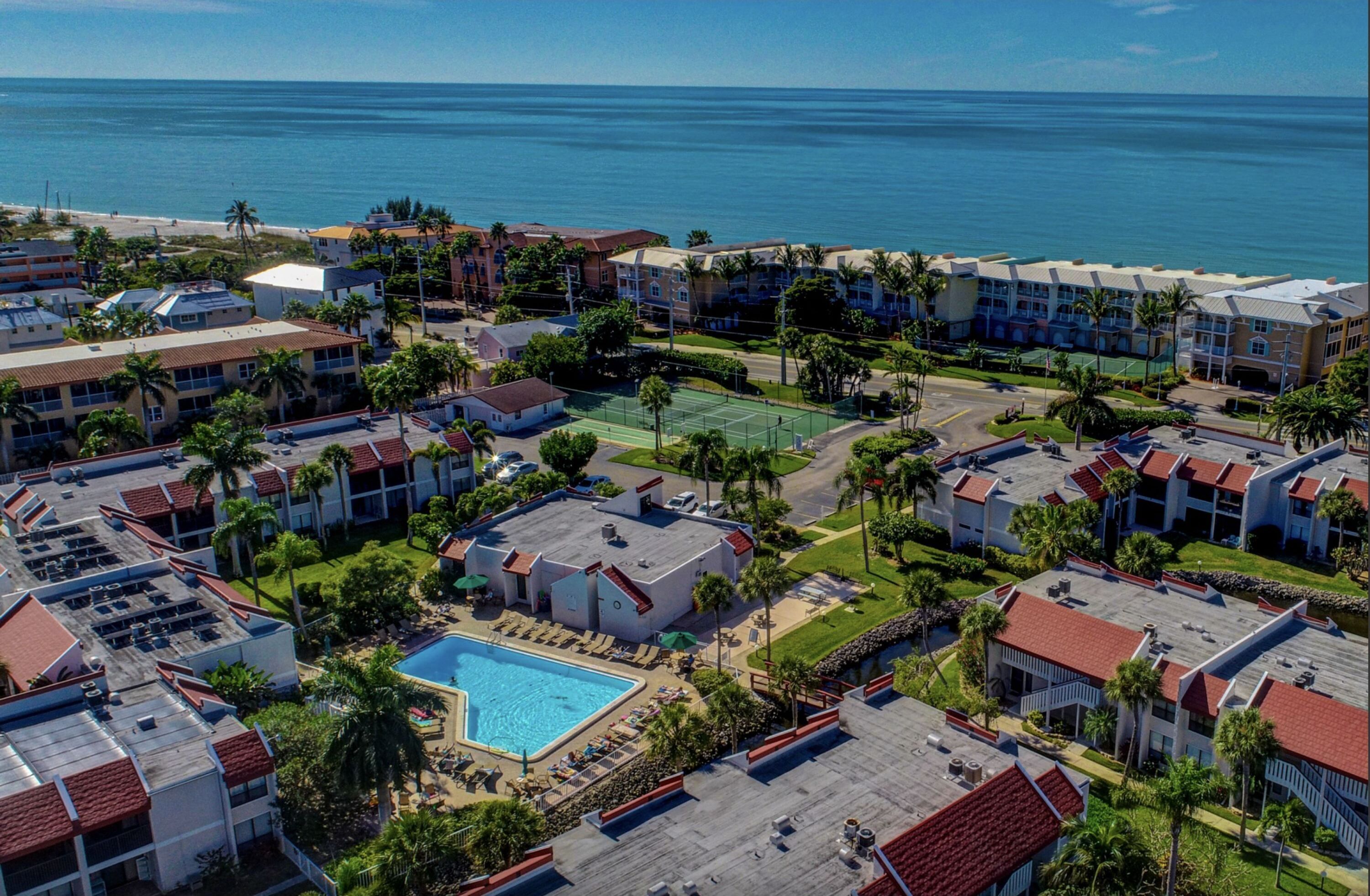 A resort with multiple buildings, a swimming pool, and a view of the ocean.