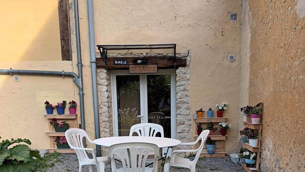 A patio area with a table and chairs, surrounded by potted plants and a gravel ground. - Studio Meublé Indépendant Dans un Ancien Moulin (Ceton)