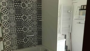 A bathroom with a freestanding bathtub, a white sink, and a patterned tile backsplash. - Studio Meublé Indépendant Dans un Ancien Moulin (Ceton)