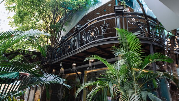 An indoor atrium with a high ceiling, curved wooden balcony, and lush green plants. - Nguyen Huong Hotel (Da Nang)