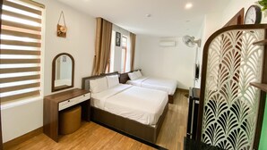 A hotel room with two beds, a wooden floor, a mirror, a desk, and a decorative screen. - Nguyen Huong Hotel (Da Nang)