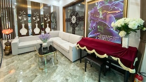 A modern living room with a white sofa, a glass coffee table, and a decorative vase with flowers. - Nguyen Huong Hotel (Da Nang)