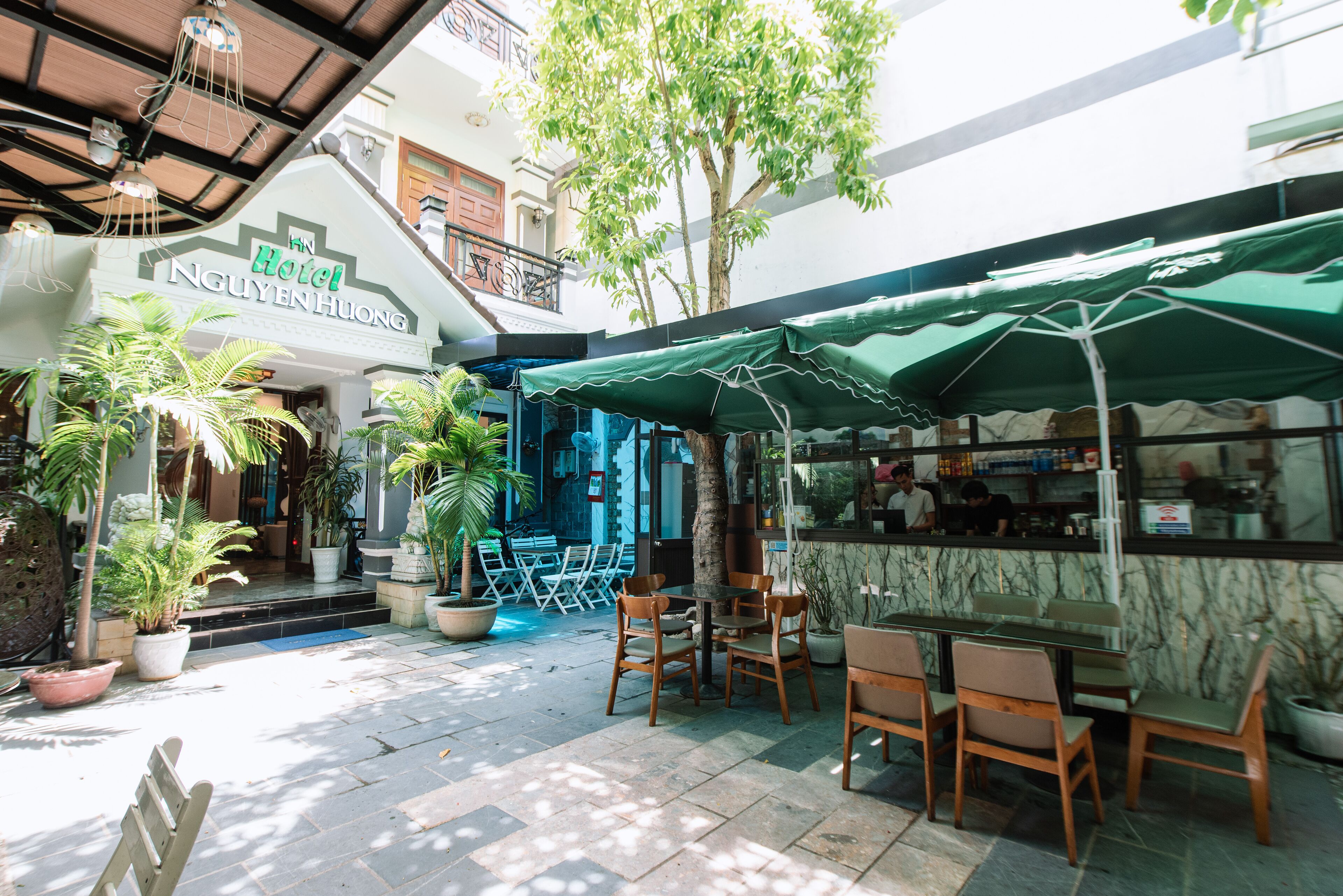 A hotel courtyard with outdoor seating, potted plants, and a covered dining area.