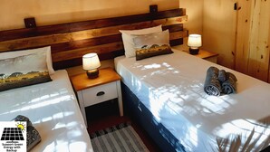Ein Hotelzimmer mit zwei Betten, Holz-Kopfteilen und Wandbildern von Elefanten.