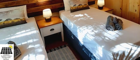 Une chambre d’hôtel avec deux lits, des têtes de lit en bois et des œuvres d’art représentant des éléphants accrochées au mur.