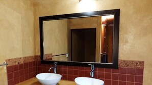 Ein Badezimmer mit zwei weißen Waschbecken, einem Spiegel und einem Handtuch auf der Ablagefläche.