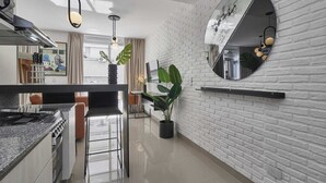 A modern kitchen with a central island, white brick walls, and a large mirror.