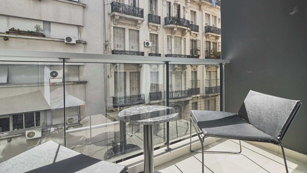 A balcony with a glass railing, a round table, and two chairs.