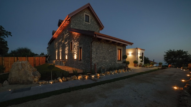 A stone house with a sloped roof, a driveway, and outdoor lighting. - Antichi Orti Del Sole (Agerola)
