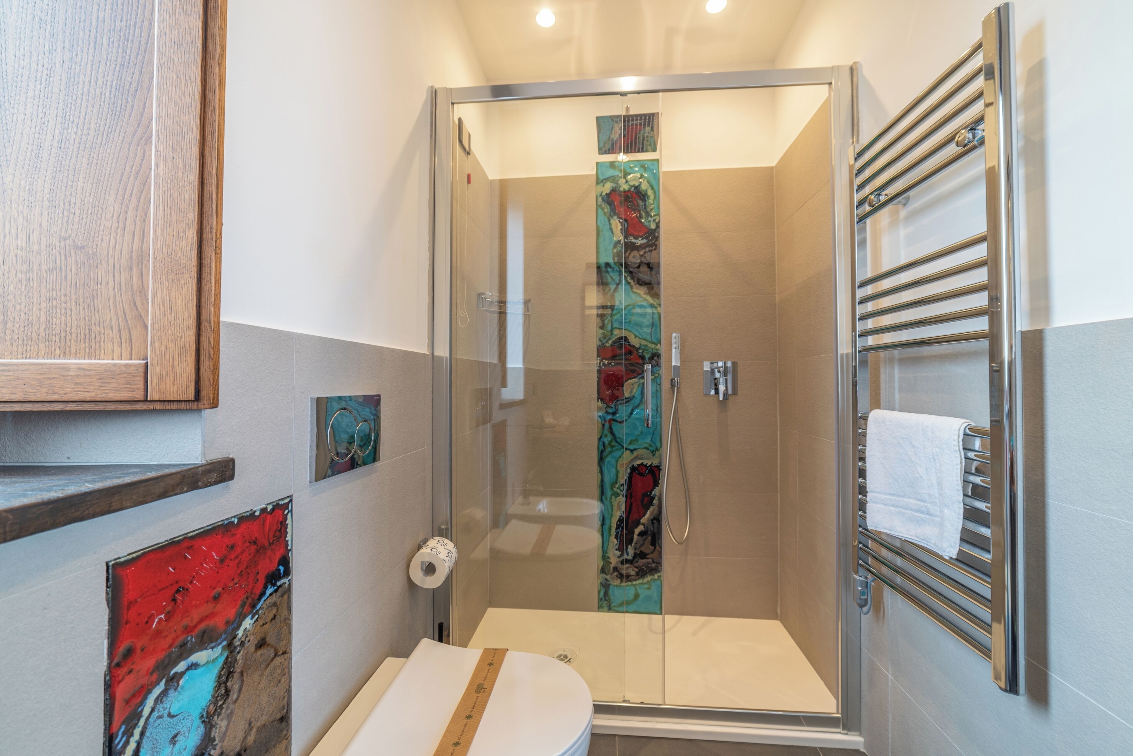 Une salle de bain moderne avec une douche à parois de verre, des toilettes et un porte-serviettes.
