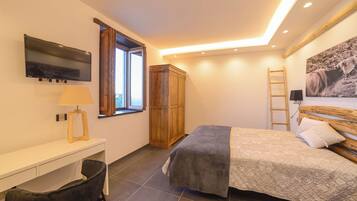 Une chambre à coucher comprenant un lit, un bureau, une chaise, une armoire, un téléviseur, une fenêtre et un tableau accroché au mur.