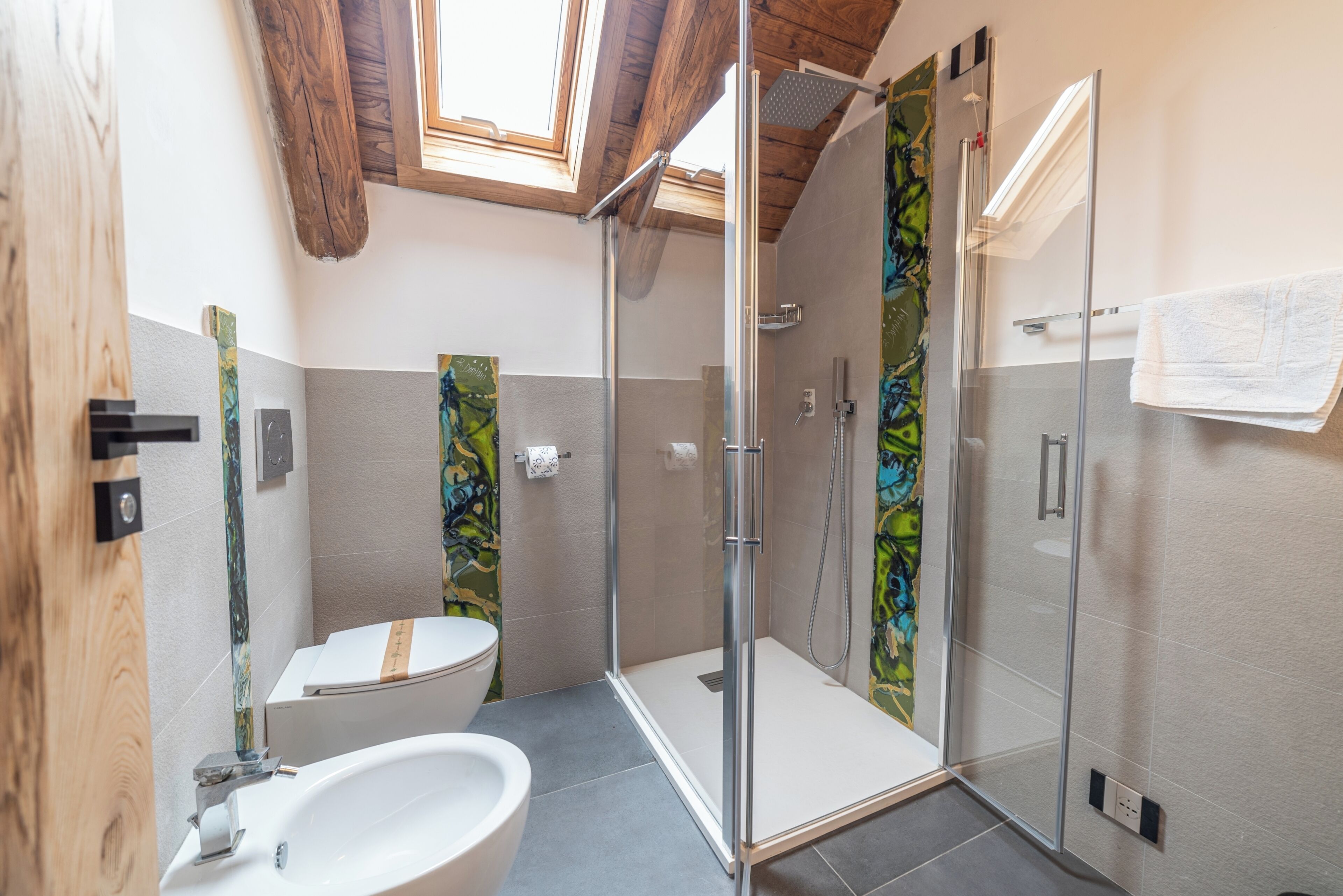 Een moderne badkamer met een douchecabine van glas, een witte wastafel en een toilet.