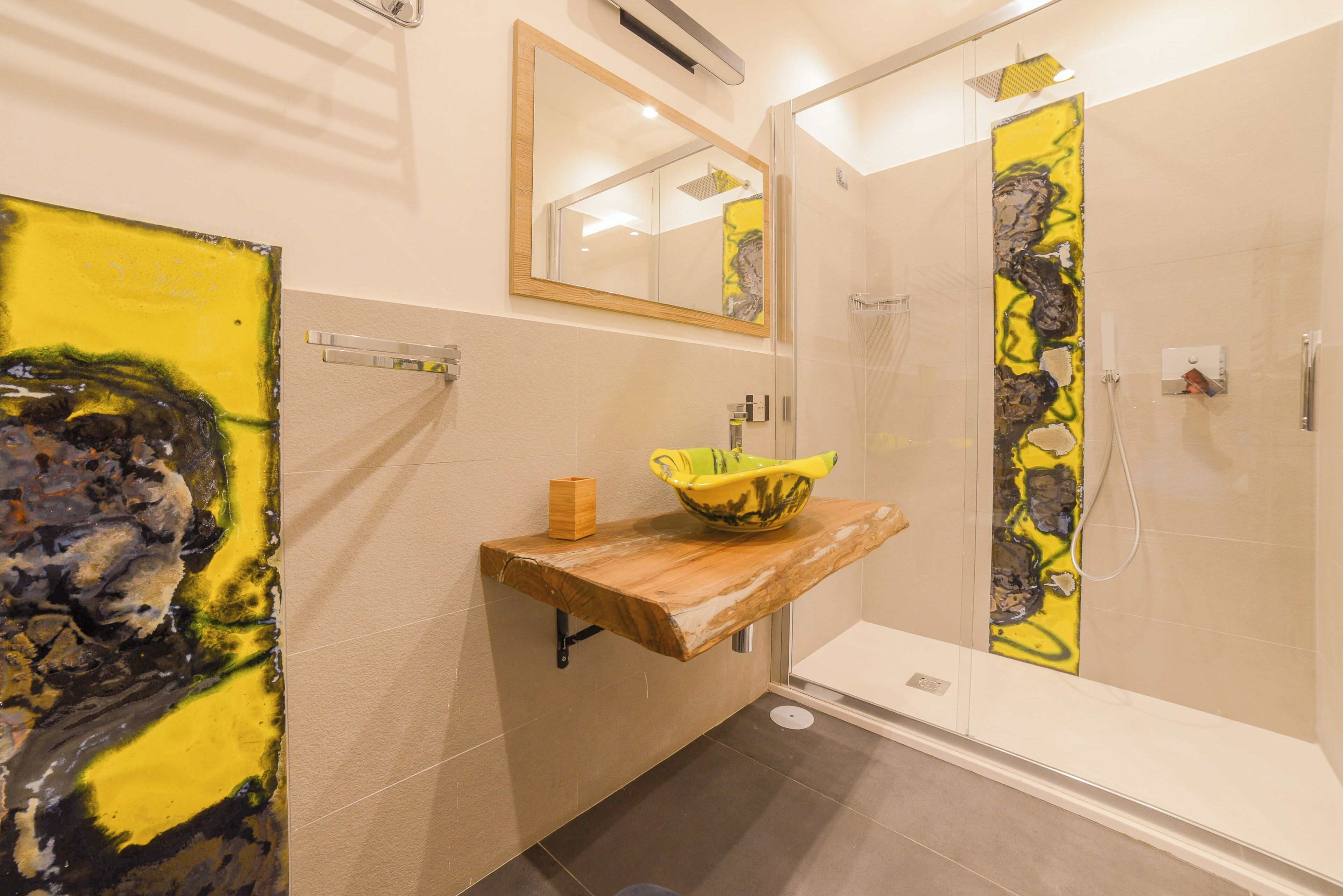 Une salle de bain avec un meuble-lavabo en bois, une cabine de douche en verre et un grand miroir.