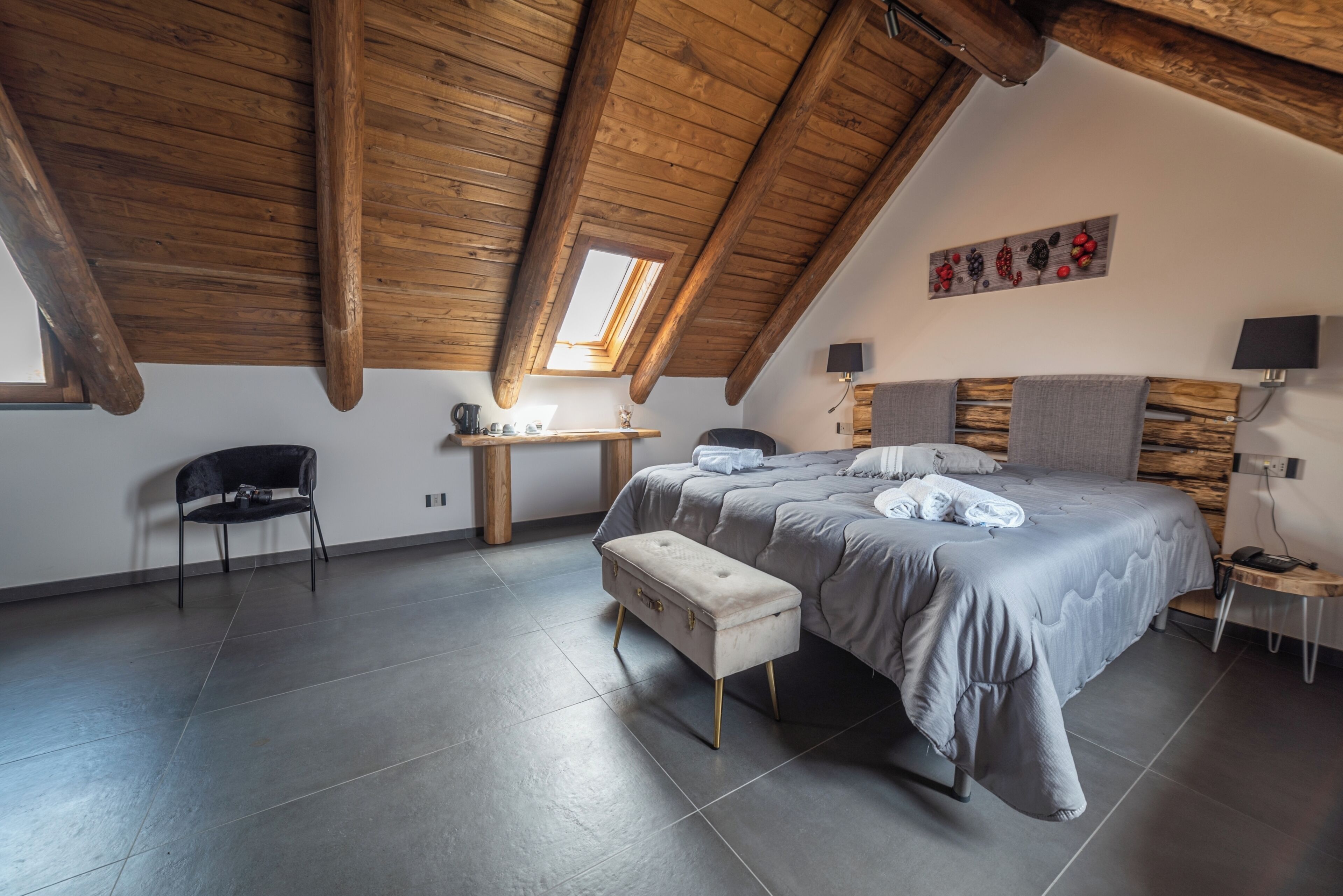 A bedroom with a large bed, a desk, a chair, and a bench.