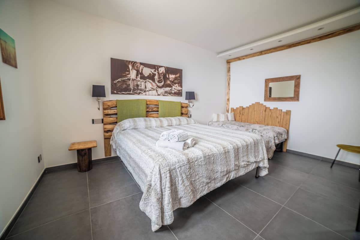 Un dormitorio con dos camas, cabeceros de madera, un cuadro, un espejo y una mesita.