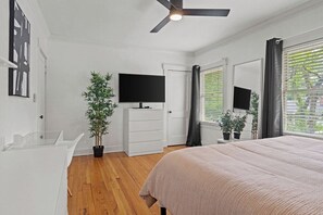 A bedroom with a bed, a television, a ceiling fan, and a window with blinds. - Entertainer - Brookside + Walkable + Firepit (Kansas City)