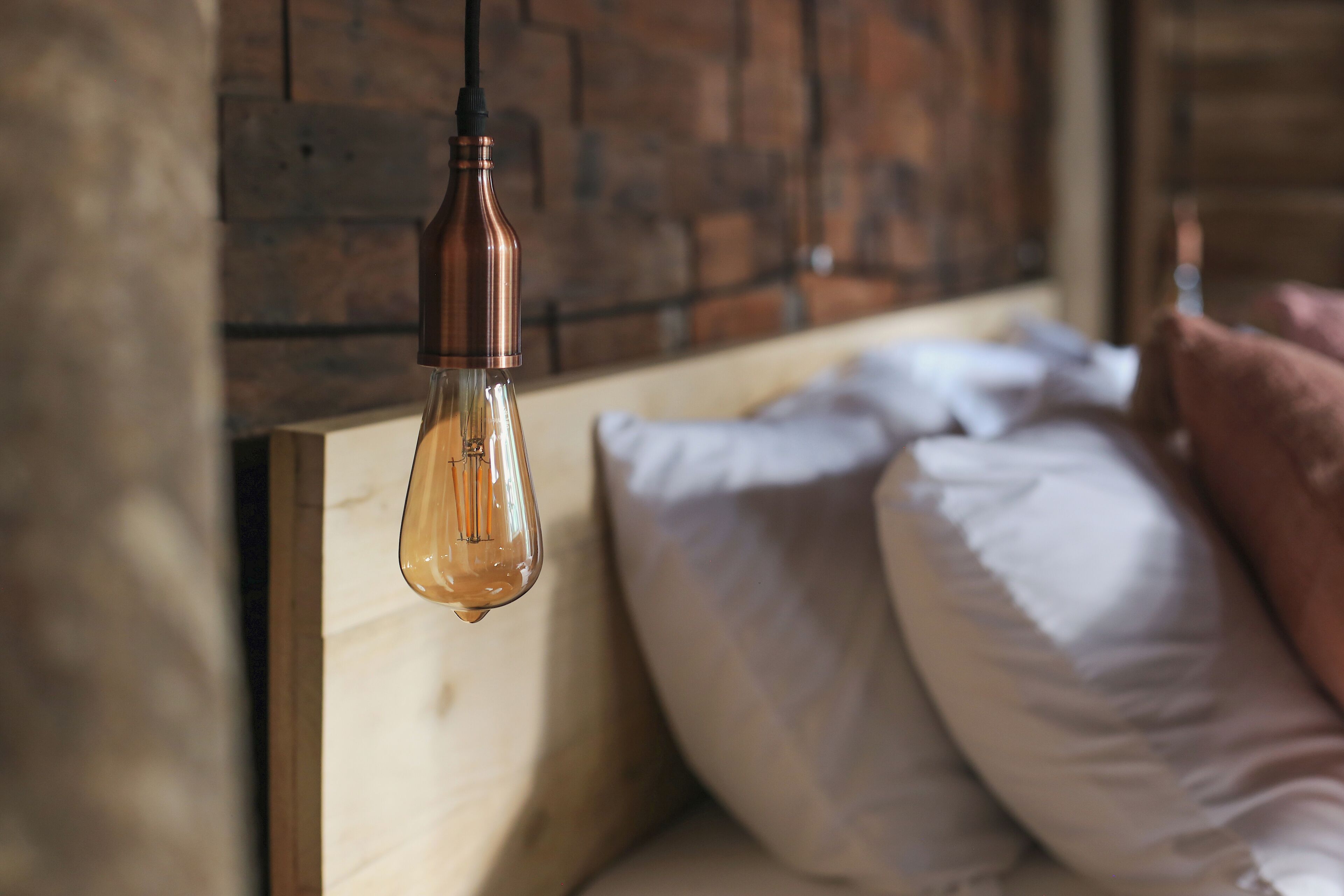 A bedroom with a wooden headboard, a hanging light fixture, and pillows.