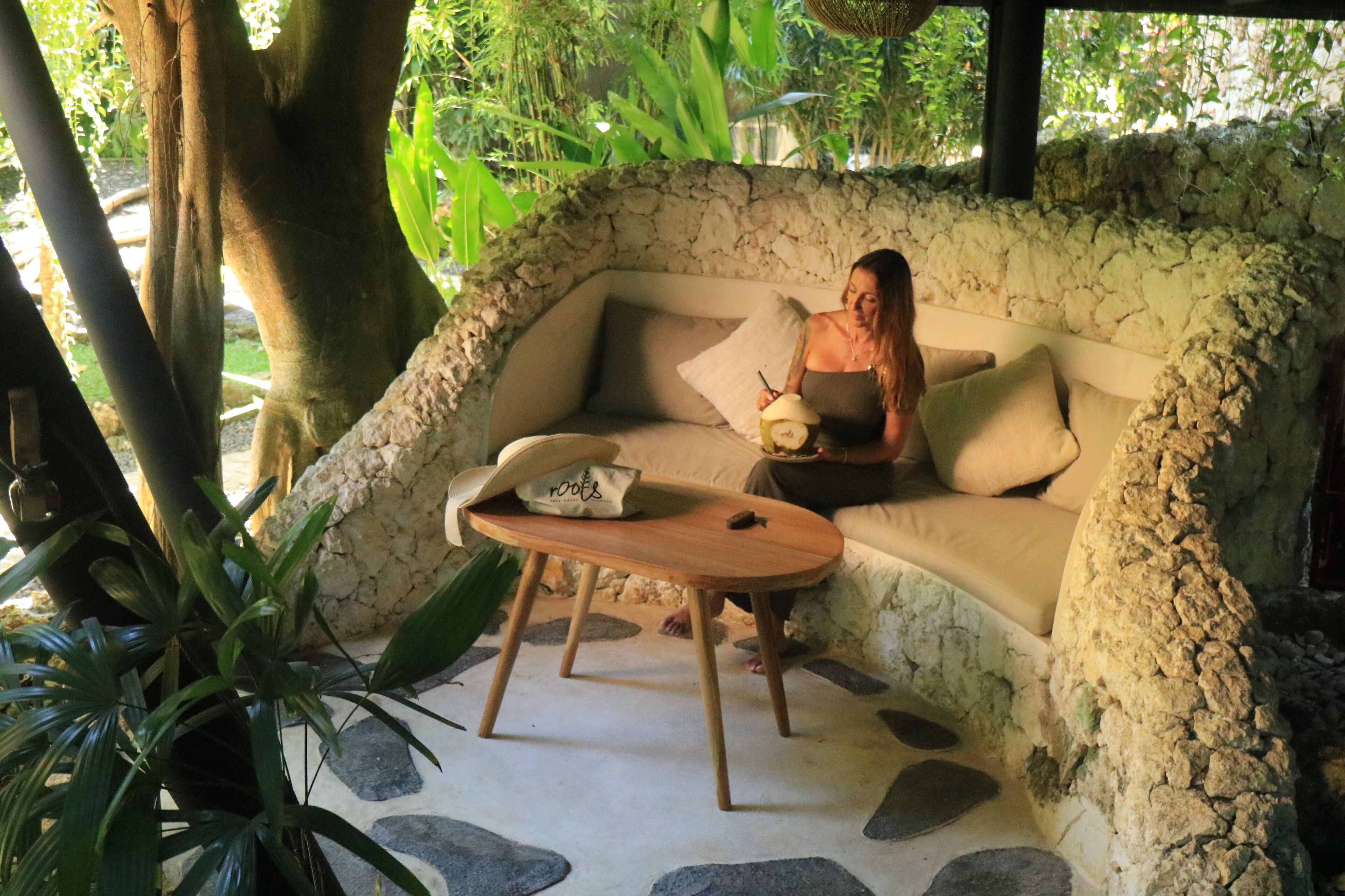 A stone-walled outdoor seating area with a sofa and a wooden table.