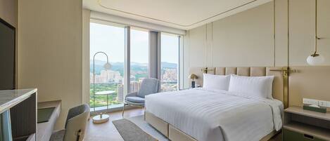 A modern hotel room with a large bed, a desk, and a chair.
