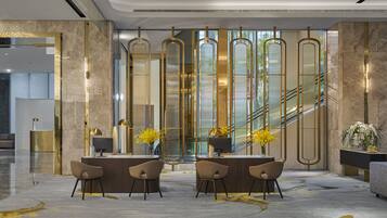 A modern lobby with a reception desk, seating area, and a staircase.