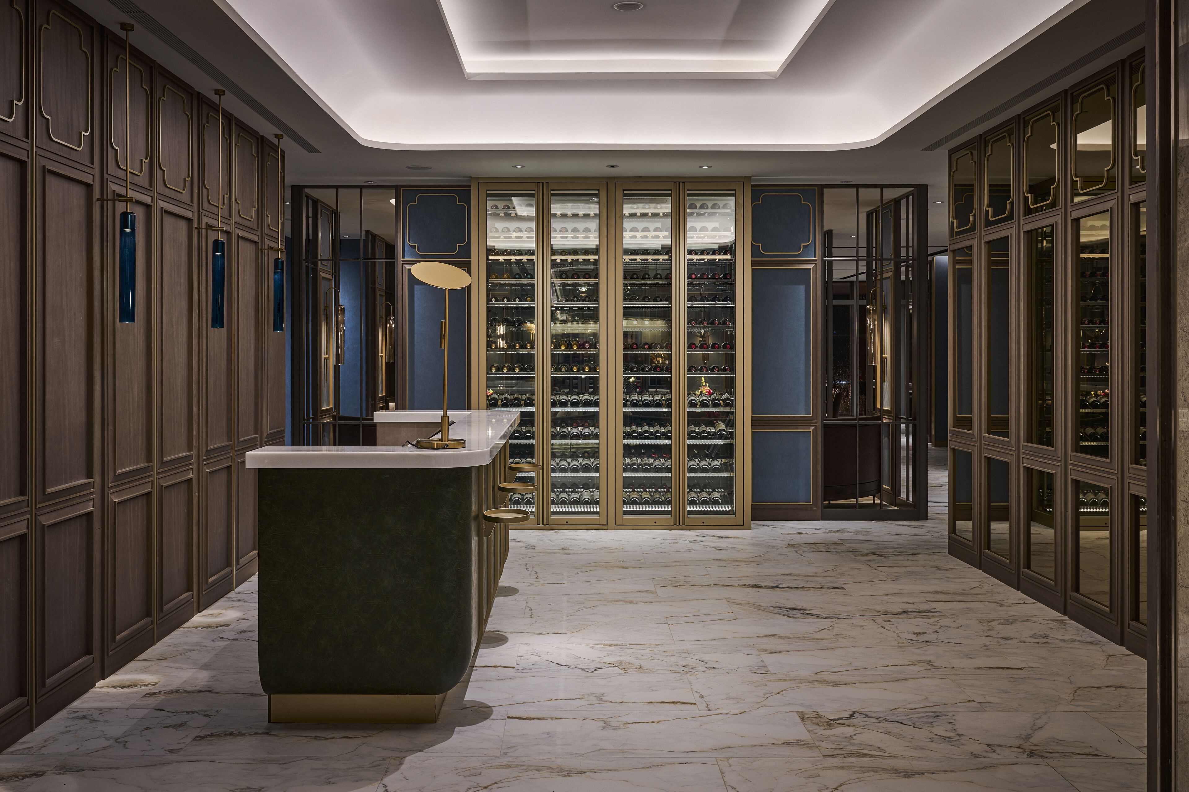 Un hall d’entrée luxueux, doté d’un sol en marbre, d’un bar central et d’une cave à vin avec des portes en verre.