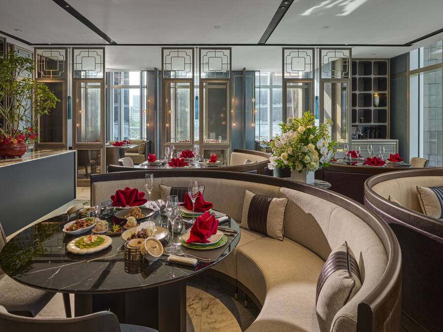 A modern dining area with a round table set for a meal, surrounded by comfortable seating.
